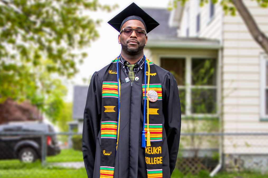 Caswell Smith standing posing in his graduation cap and gown