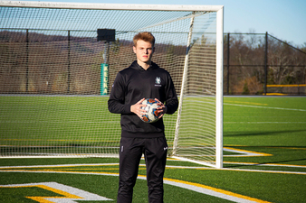 Carson Smith '26 holding soccer ball in front of goal on Keuka College's soccer field